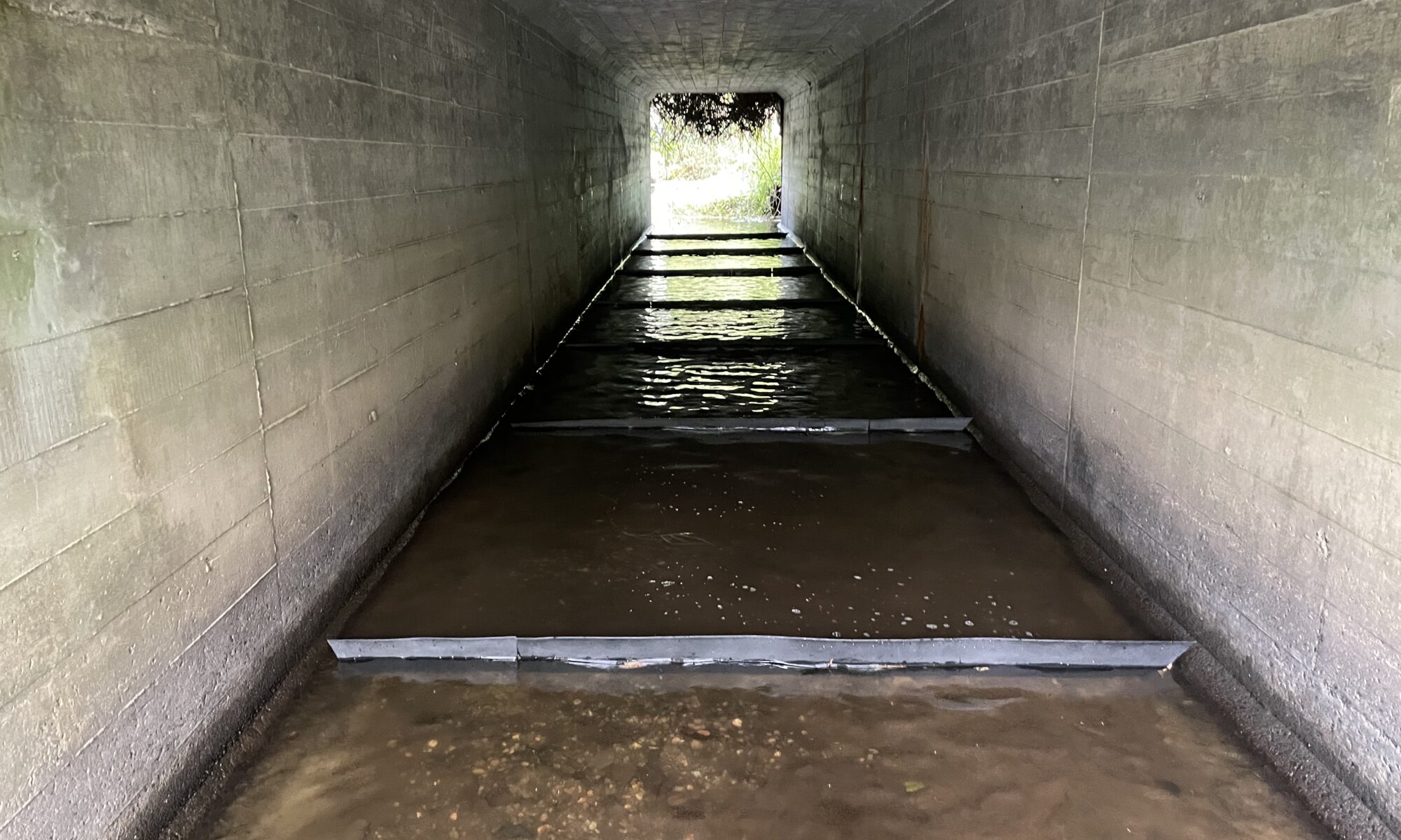 Interior of concrete box culvert with completed FlexiBaffle baffle installation creating stepped fish passage pools